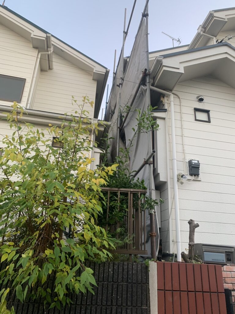 工事をする住宅と左隣の家の境目に養生シートがある。