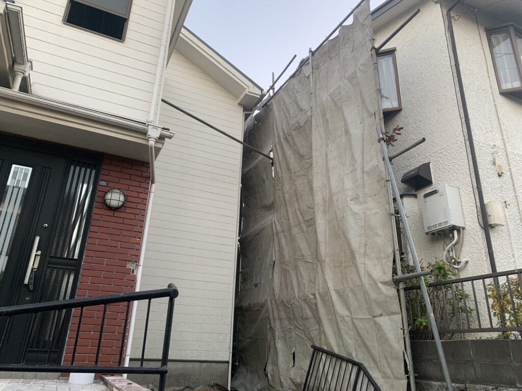 工事をする家と右隣の家の境目の養生シートの写真。