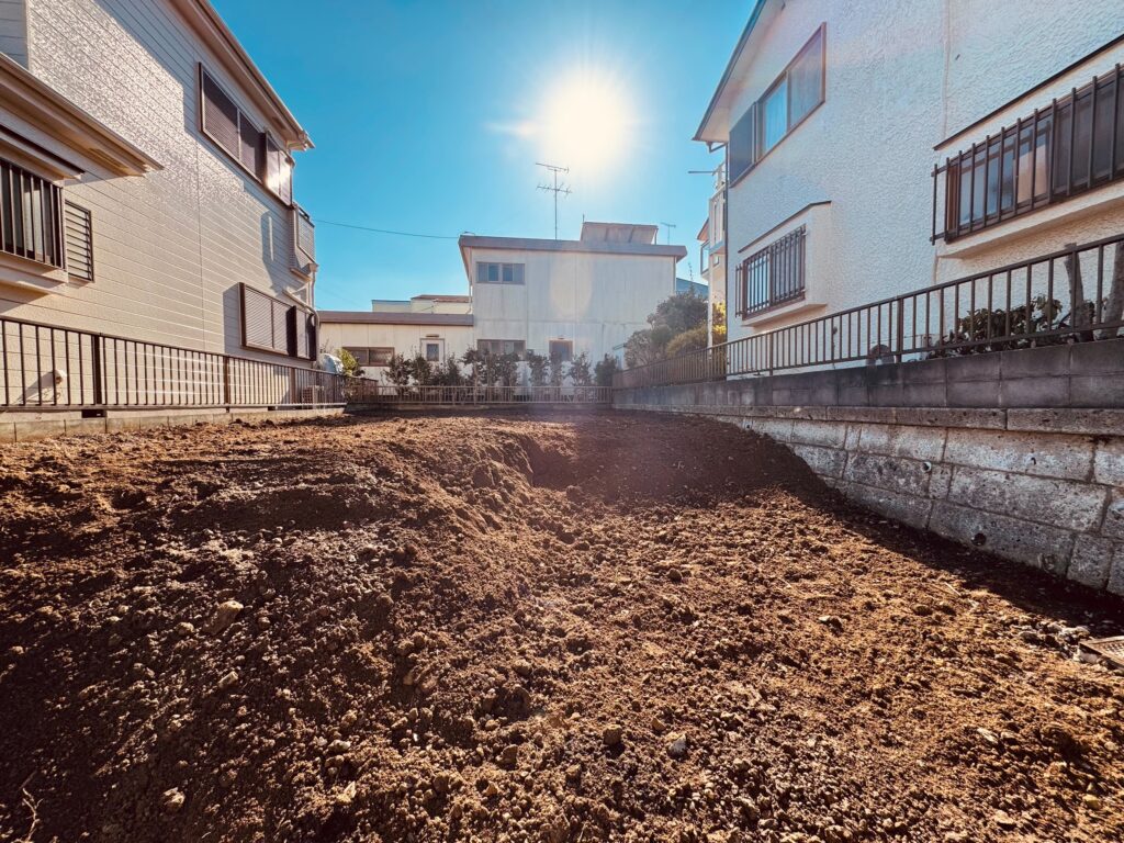 建物の解体が完了し、土が見える状態。奥で太陽が輝いている。