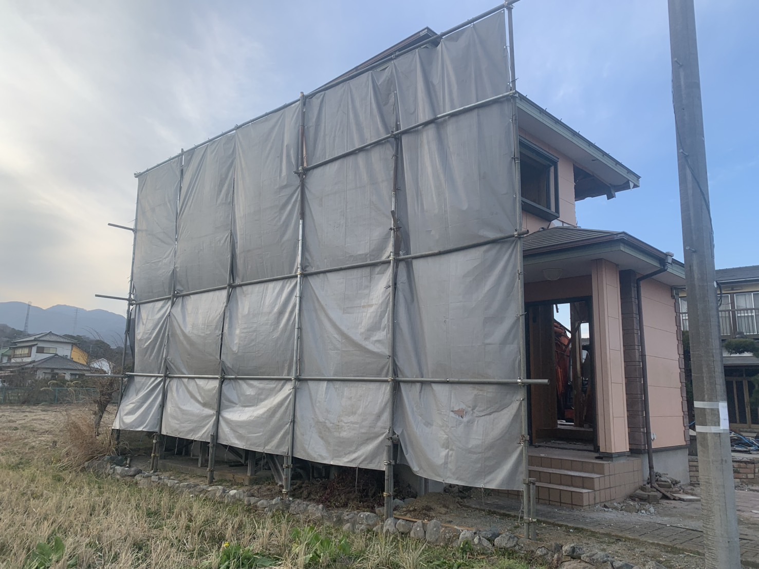 建築用シートで覆われた解体工事中の木造住宅